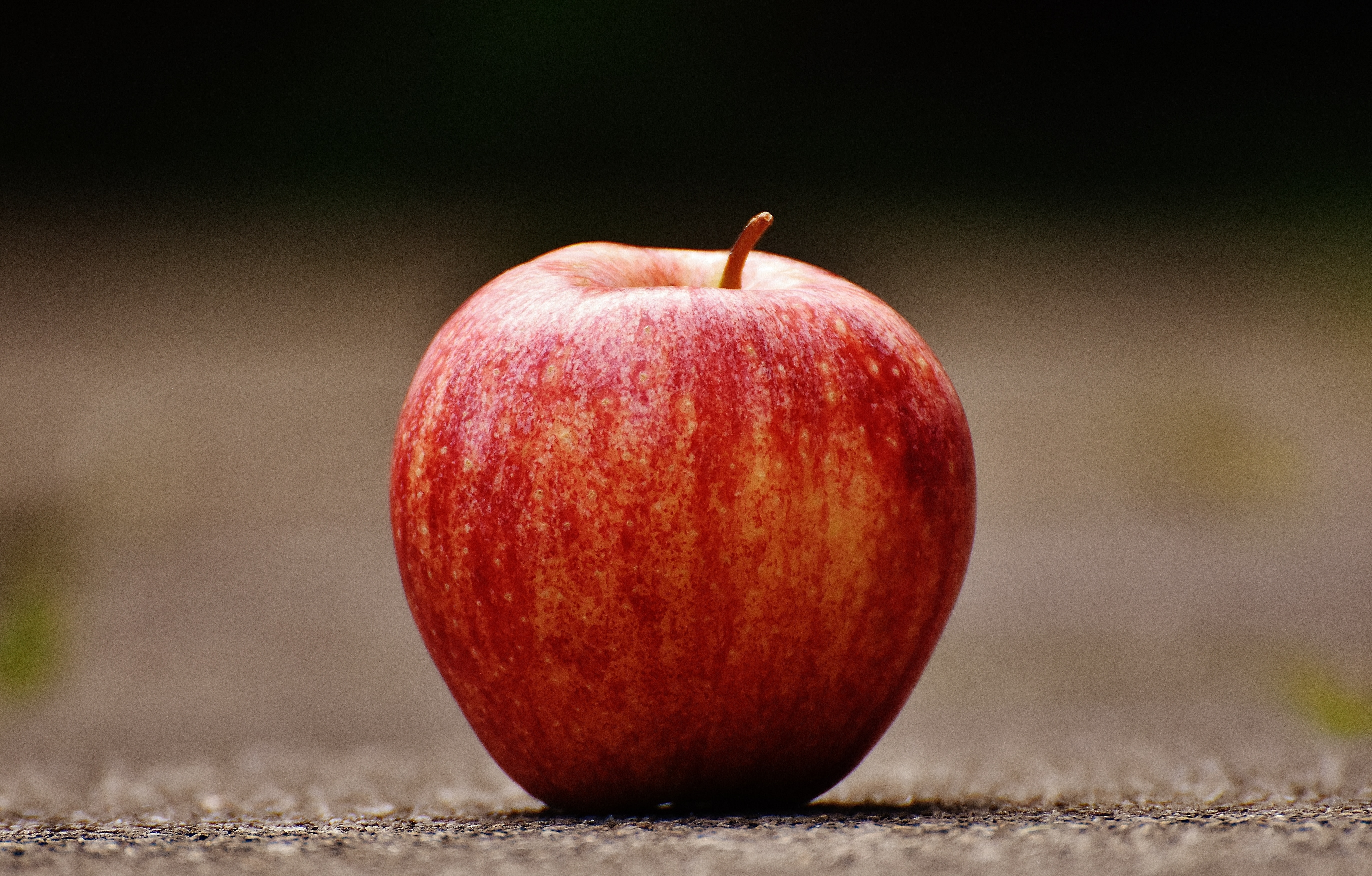 shallow-focus-photography-of-red-apple-on-gray-pavement
