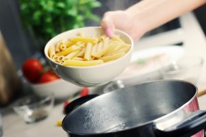 person holding white ceramic bowl with pasta