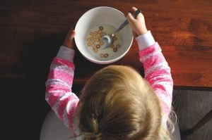 child with an almost empty white bowl of cereal and milk