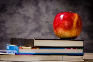 stack of school books with an apple on top